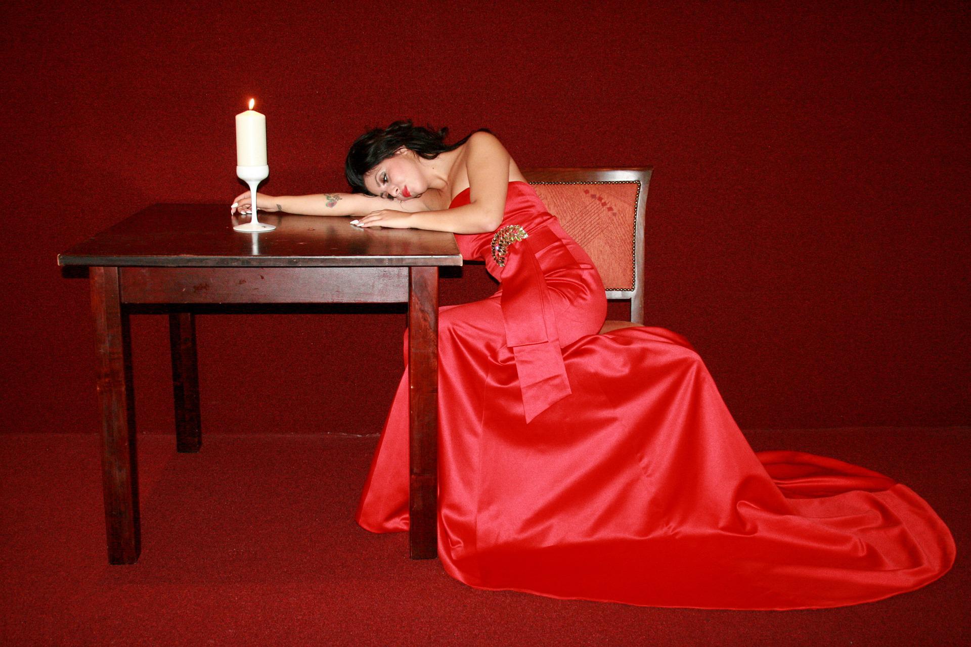 Ha nem hív fel... 1 sad woman in a red gown hunching on a table next to a candle